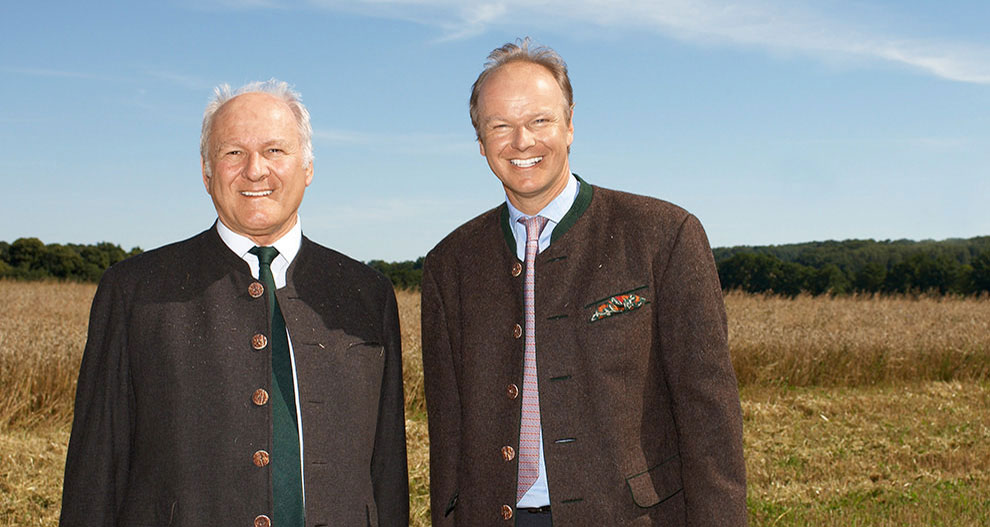 Twee mannen in pakken staan in een veld.