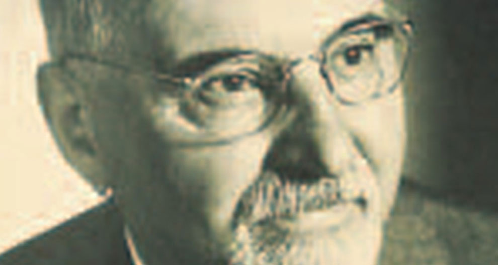 Een close-up van het gezicht van een man met zijn ogen, neus en mond, met een baard en snor en een bril.