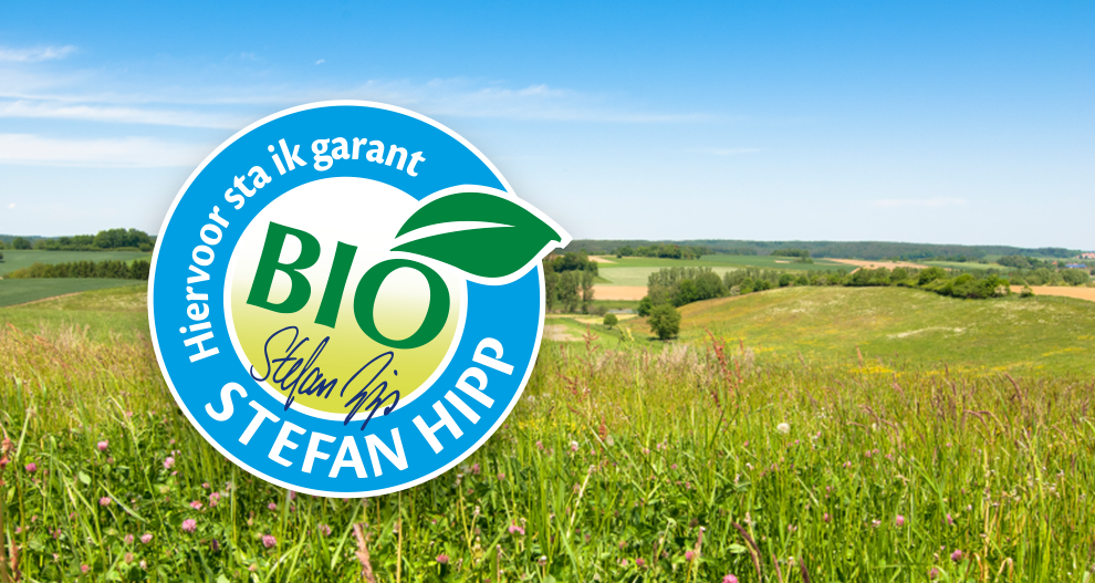 Een landschap met glooiende heuvels en velden is bedekt met een blauw cirkelvormig logo met het woord "BIO" en de naam "Stefan Hipp".