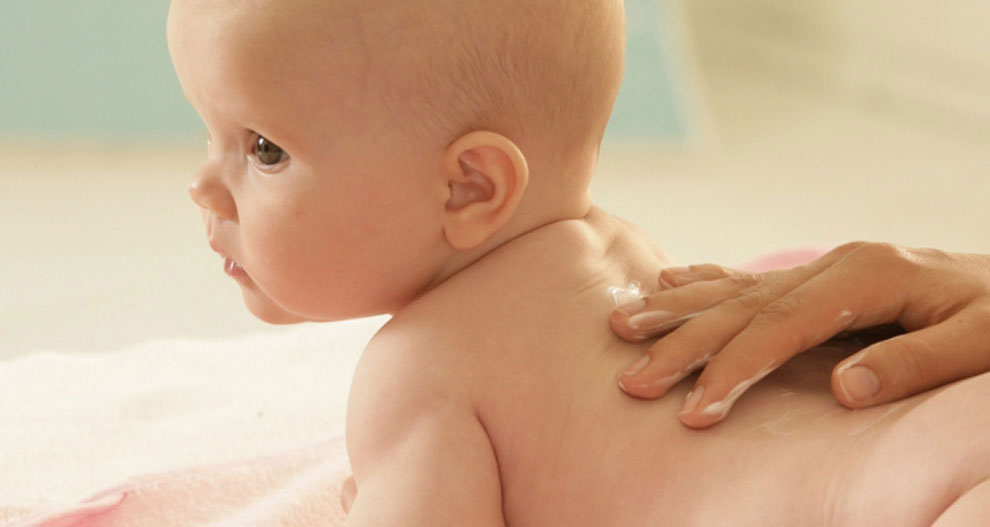 Een baby wordt gemasseerd met lotion.