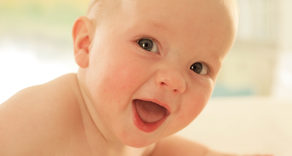 Een baby met een wijd open mond en een nieuwsgierige uitdrukking.