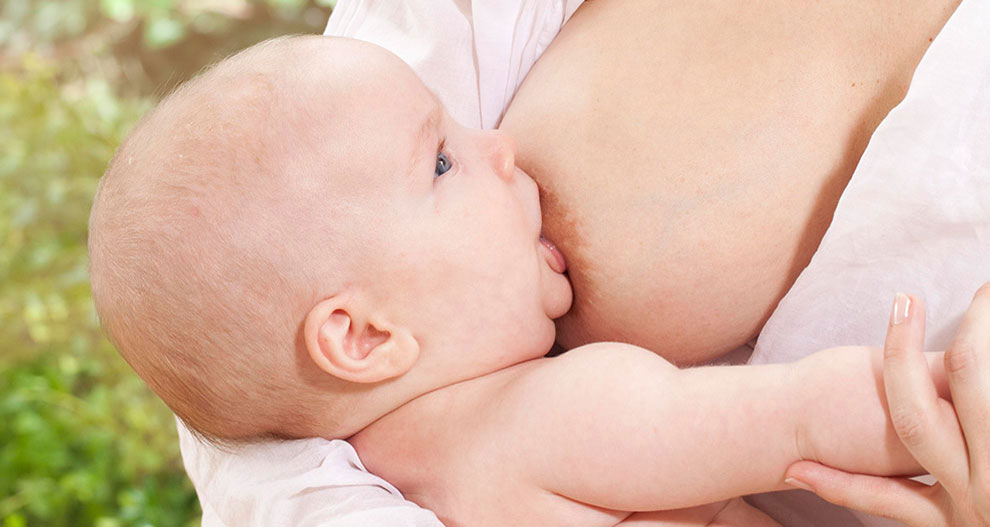 Een baby krijgt borstvoeding van een vrouw.