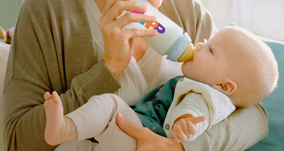 Een vrouw voedt een baby met een fles.