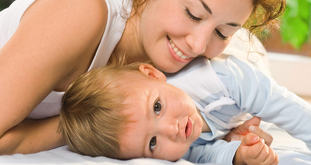 Een vrouw en een baby liggen op een bed.