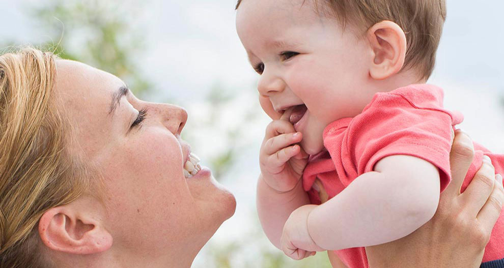 Een vrouw houdt een baby vast, beiden kijken elkaar aan.