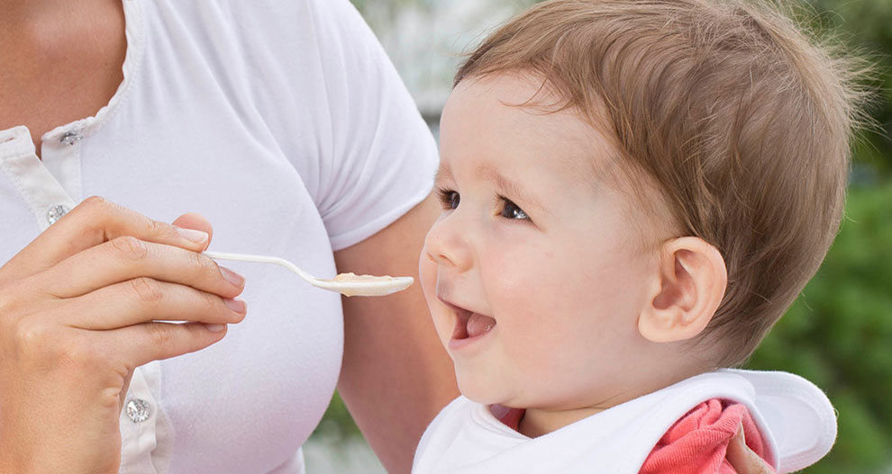 Iemand voedt een baby met een lepel.