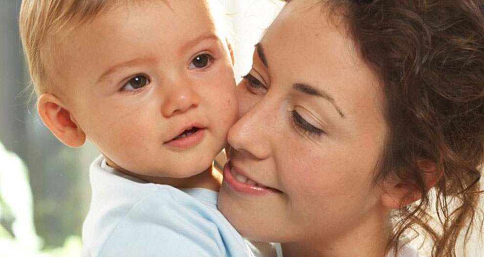 Een vrouw houdt een baby liefdevol dicht tegen haar gezicht.