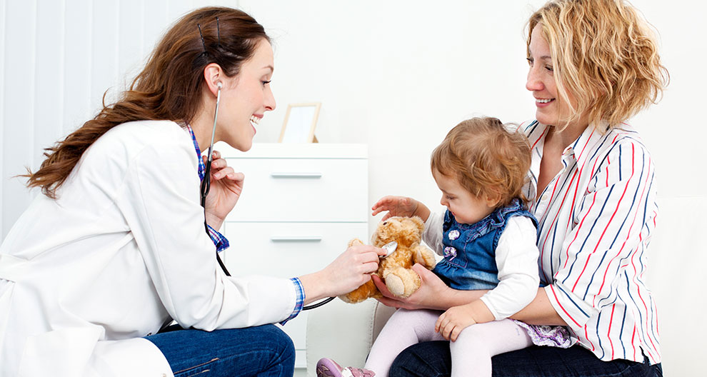 Een medewerker in de gezondheidszorg heeft interactie met een kind en een vrouw in een klinische omgeving.