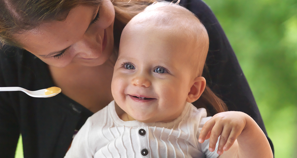 Een vrouw voedt een baby met een lepel.