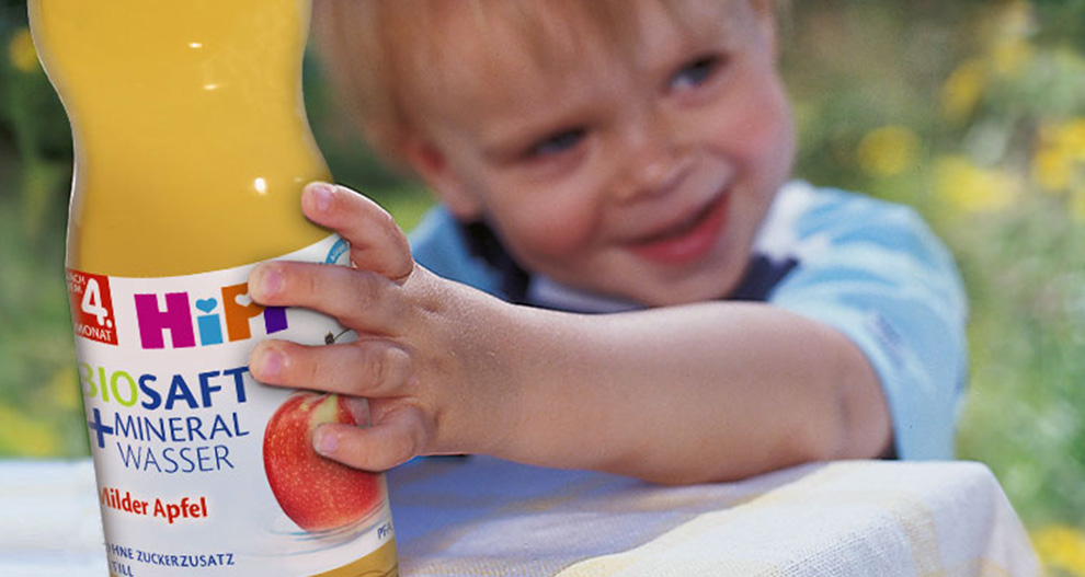 Een kinderhand houdt een fles appelsap vast.