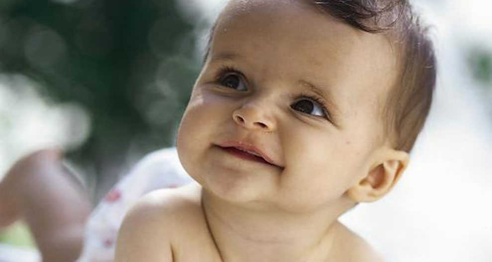 Een baby met een nieuwsgierige uitdrukking kijkt omhoog.