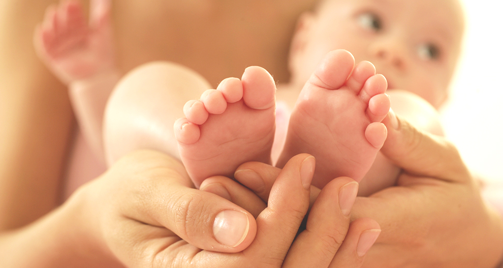 Een paar handen houdt de voeten van een baby vast.
