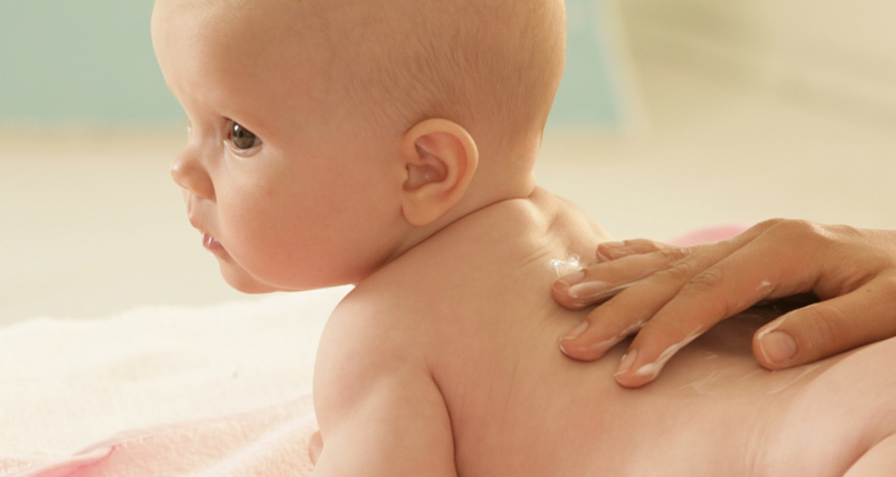 Een baby wordt gemasseerd met lotion.