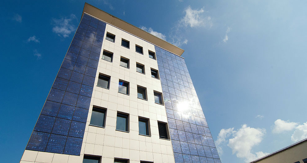 Een modern gebouw met een witte en blauwe gevel staat onder een heldere hemel met een paar wolken.