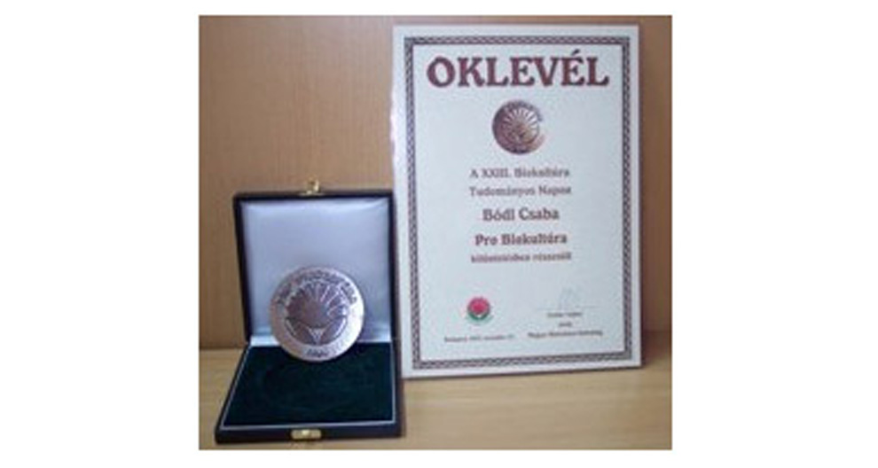 Een certificaat en een medaille worden tentoongesteld in een koffer.