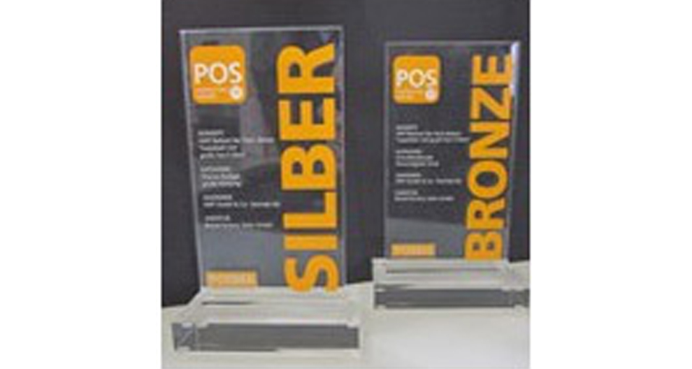 Twee verticale doorzichtige plaquettes met oranje tekst, de ene met de tekst "SILBER" (ZILDER) en de andere met de tekst "BRONZE" (BRONS), staan op een wit oppervlak tegen een donkere achtergrond.